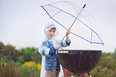 Buy stock photo Cropped portrait of a young boy standing in front of an outdoor grill in the rain