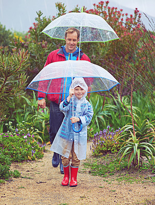 Buy stock photo Full length shot of a father and his son walking outside in the rain