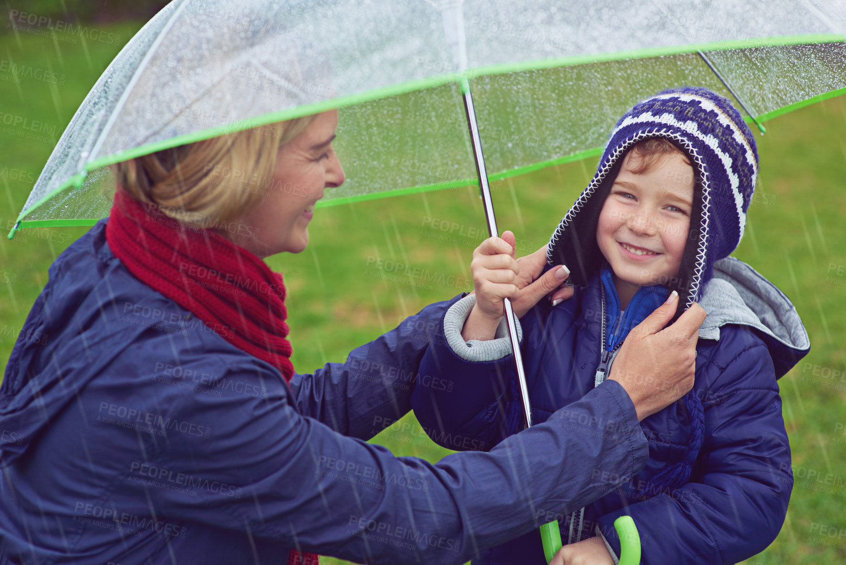 Buy stock photo Cropped shot of a mother making sure her son is covered while outside in the rain
