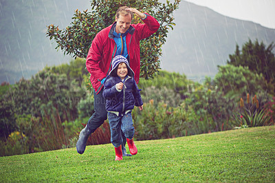 Buy stock photo Full length shot of a father and his son running outside in the rain