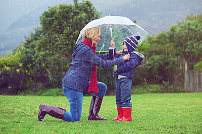 Buy stock photo Full length shot of a mother making sure her son is covered while outside in the rain