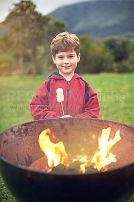 Buy stock photo Portrait of a little boy roasting a marshmallow over a fire