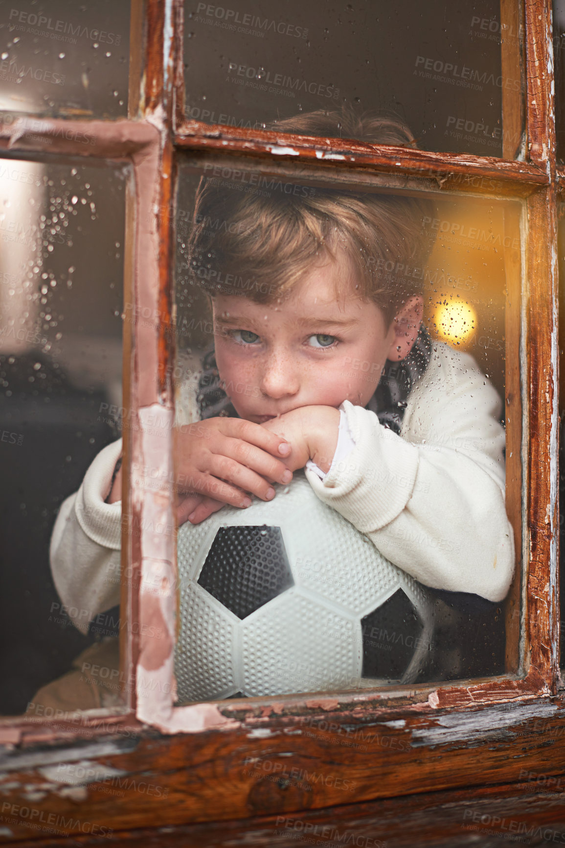 Buy stock photo Thinking, depressed and sad child by window with anxiety for bullying trauma, soccer ball and scared with stress. Orphan, football and young boy by glass for lonely and ideas for adoption in Ireland