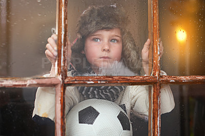 Buy stock photo A young boy sitting by the window and looking bored while it rains outside