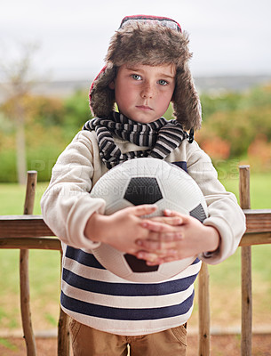 Buy stock photo Shot of a little boy standing outside with his soccer ball
