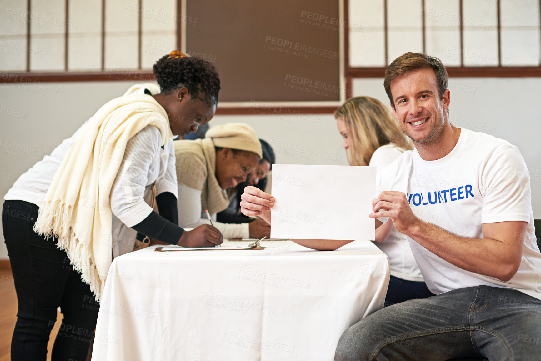 Buy stock photo Cropped portrait of a volunteer holding an empty sign while volunteers get signatures in the background