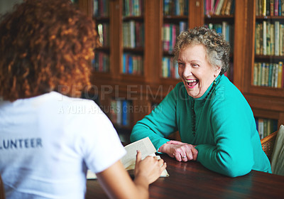 Buy stock photo Shot of a volunteer reading to a senior woman at a retirement home