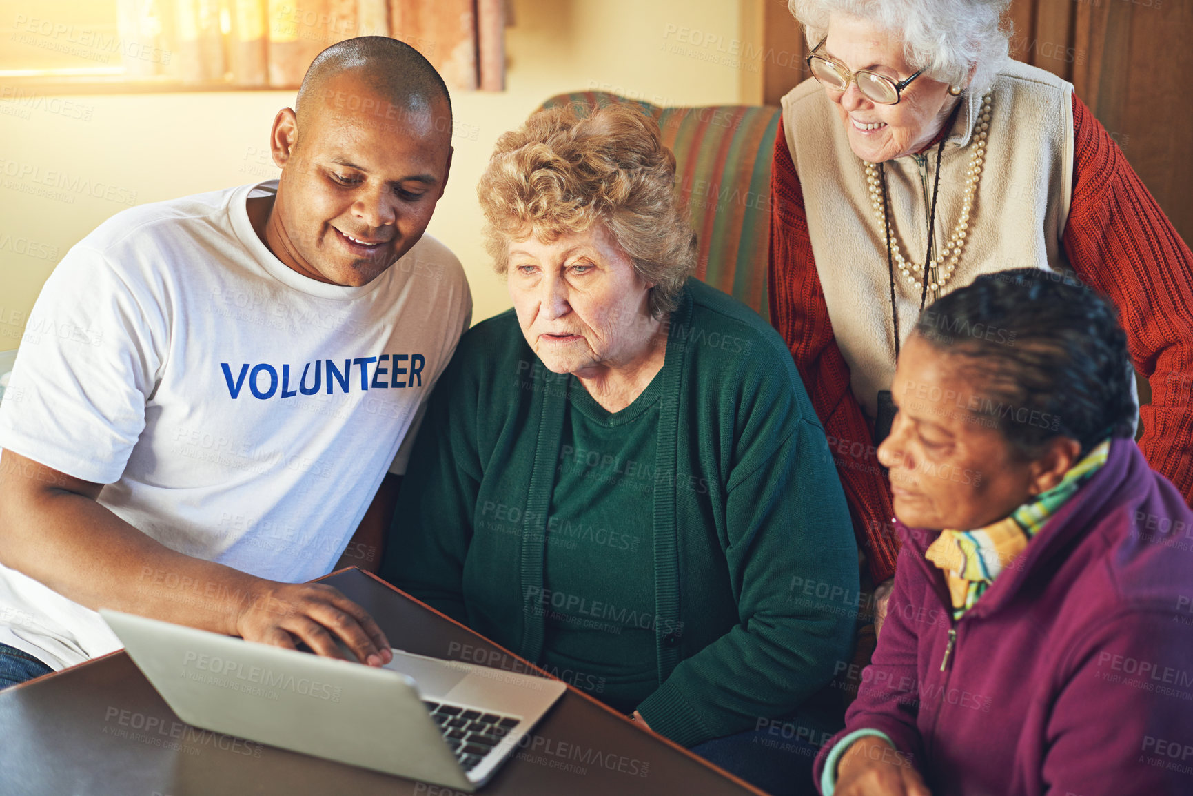 Buy stock photo Shot of a volunteer showing a group of senior women how to use a laptop