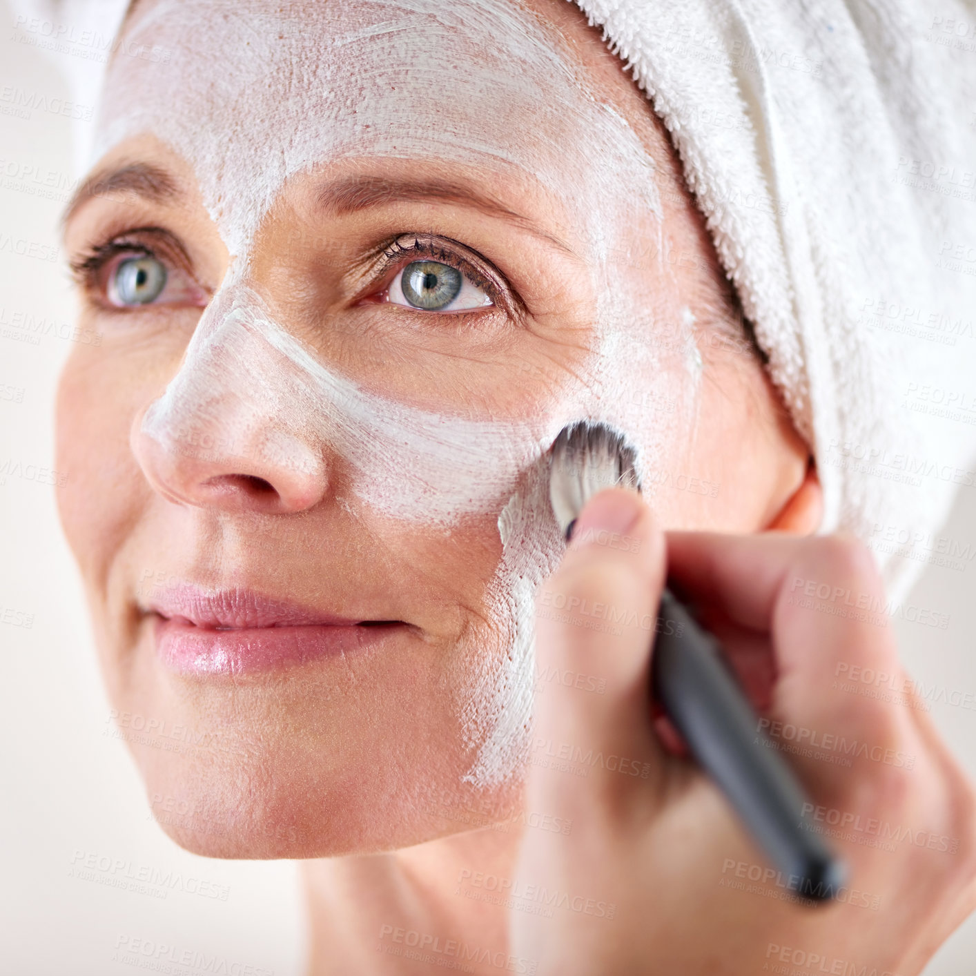 Buy stock photo Mature woman, face mask and brush with happiness in studio for skincare or anti aging on self care, wellness and fresh skin. Closeup, female person and glow with smile for facial and beauty or luxury