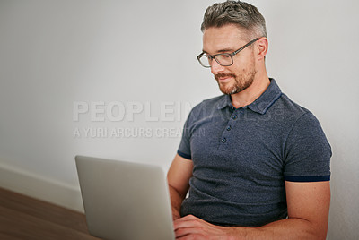 Buy stock photo Man, floor and wall on laptop with sitting for relax in casual for social media with technology for internet. Male person, glasses and house with website for blog with typing for freelance writing