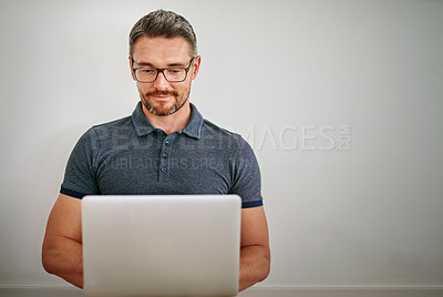 Buy stock photo Man, wall and freelance with smile on laptop in casual for relax with social media on internet for technology. Male person, glasses and house with blog for website with typing for writer career