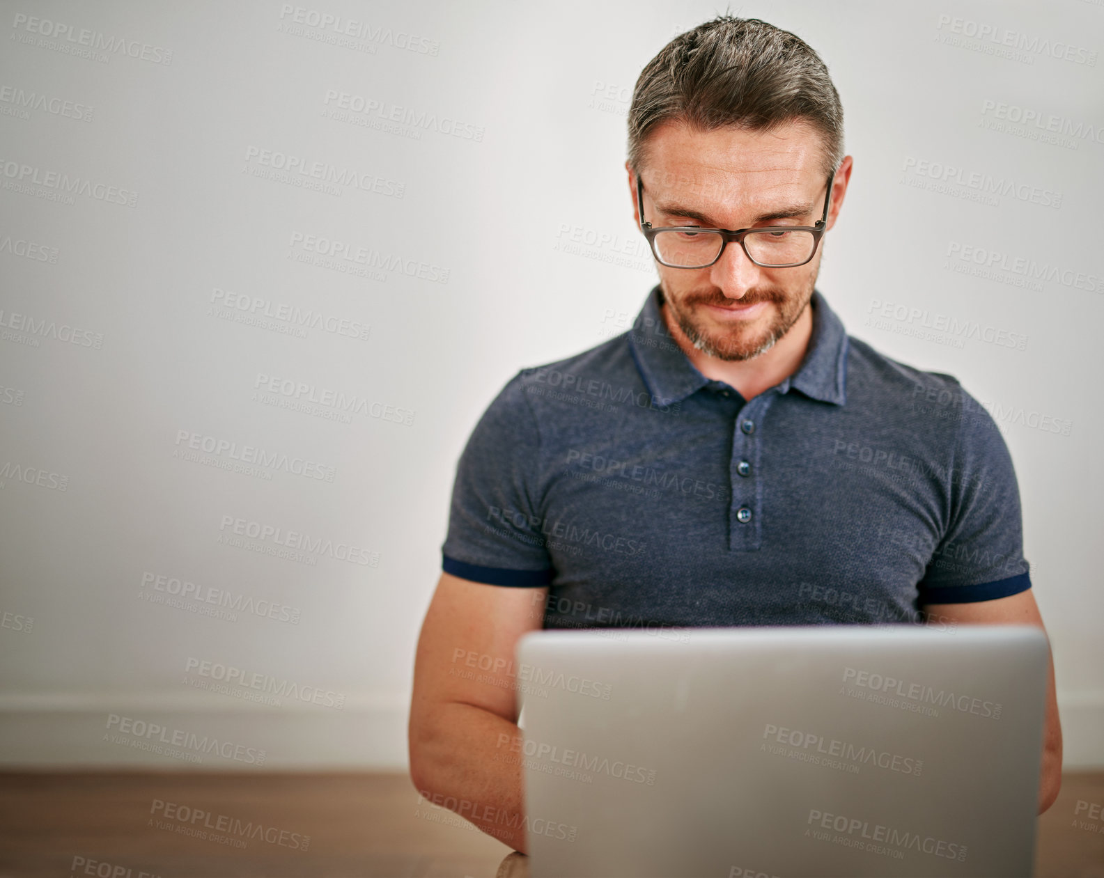 Buy stock photo Man, wall and sitting on floor with laptop for relax in casual for writing with internet for technology. Male person, glasses and house with blog for website with typing, marketing and interior