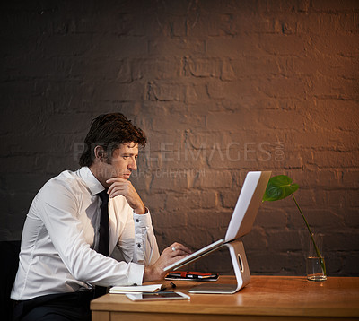 Buy stock photo Shot of a businessman working on his laptop after hours