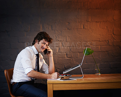 Buy stock photo Shot of a businessman talking on the phone while working late at the office