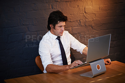 Buy stock photo Shot of a businessman working on his laptop late at night
