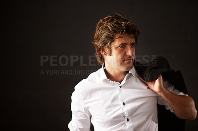 Buy stock photo Shot of a well dressed businessman carrying his jacket against a dark background