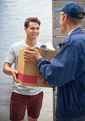 Buy stock photo Shot of a young man receiving a cardboard box from a delivery man