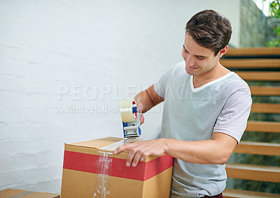 Buy stock photo Shot of a young man packing up his belongings into boxes before moving out