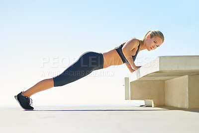 Buy stock photo Full length shot of a young woman doing pushups outside