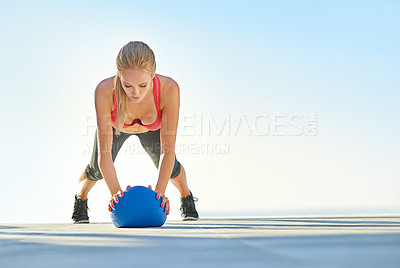 Buy stock photo Full length shot of a young woman doing pushups with a medicine ball