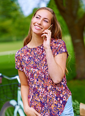 Buy stock photo Shot of a young woman using a phone while out for a cycle in the park