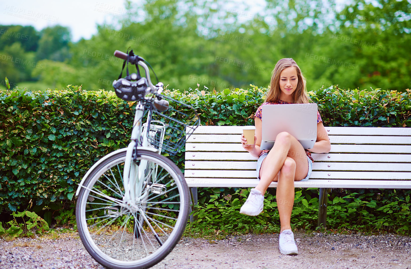 Buy stock photo Laptop, bike and woman on bench in park with coffee, smile and online connectivity for freelance project. Remote work, relax and happy girl checking email with bicycle, computer and drink in nature