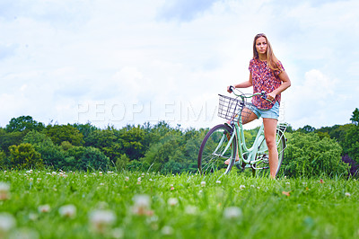 Buy stock photo Shot of a young woman cycling in the countryside