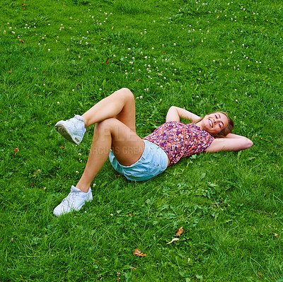 Buy stock photo Shot of a young woman relaxing on the grass in a park