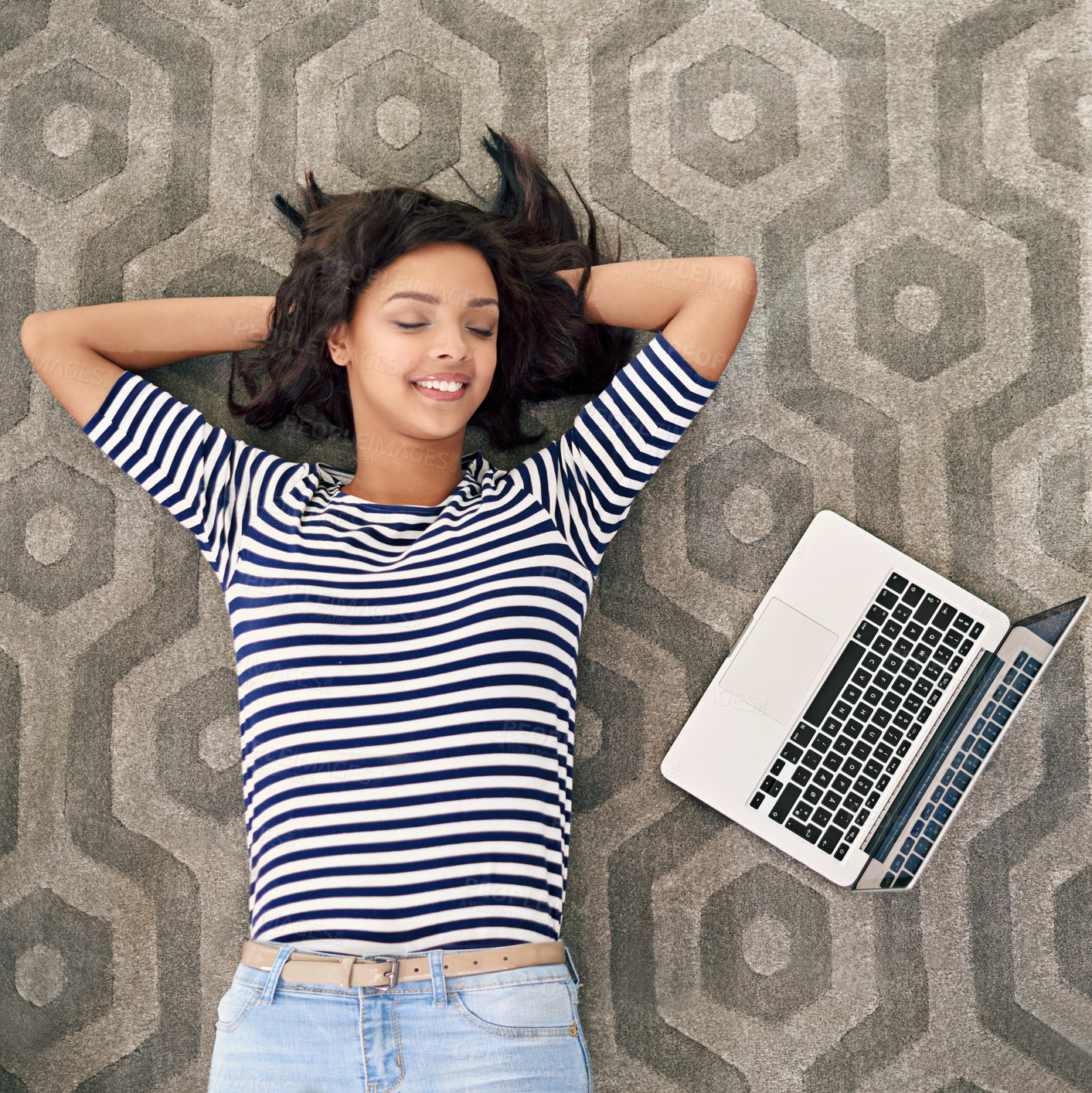 Buy stock photo High angle shot of a young woman lying beside her laptop on the floor