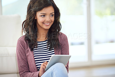 Buy stock photo Shot of a young woman using her digital tablet while sitting on the floor