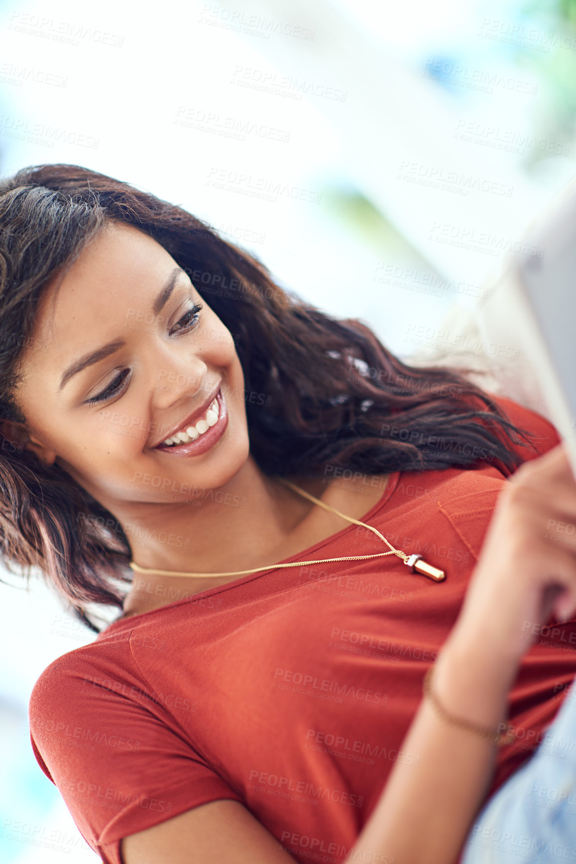 Buy stock photo Cropped shot of a young woman using her tablet while relaxing at home