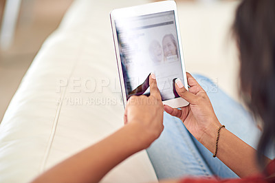 Buy stock photo High angle shot of a young woman using her tablet while relaxing at home