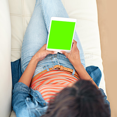 Buy stock photo High angle shot of a young woman using her digital tablet while sitting on the sofa