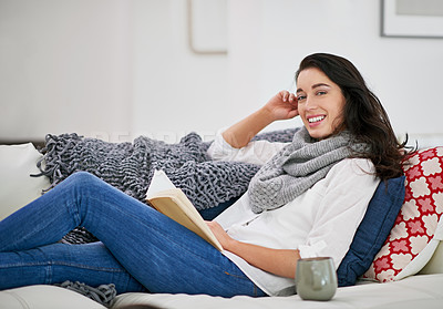 Buy stock photo Shot of a young woman reading a book while sitting in the living room