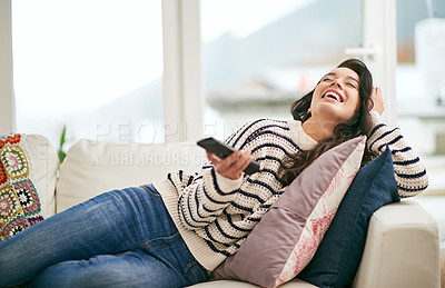 Buy stock photo Shot of a young woman relaxing at home with the remote control in her hand