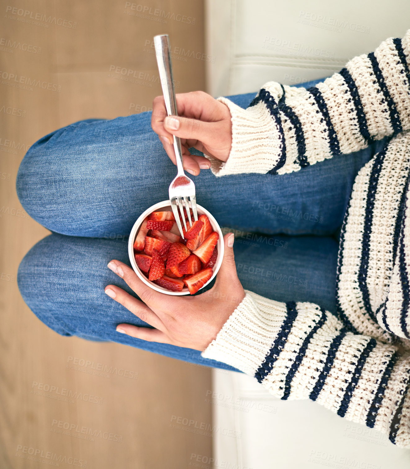 Buy stock photo Cropped shot of a woman eating a bowl of strawberries at home