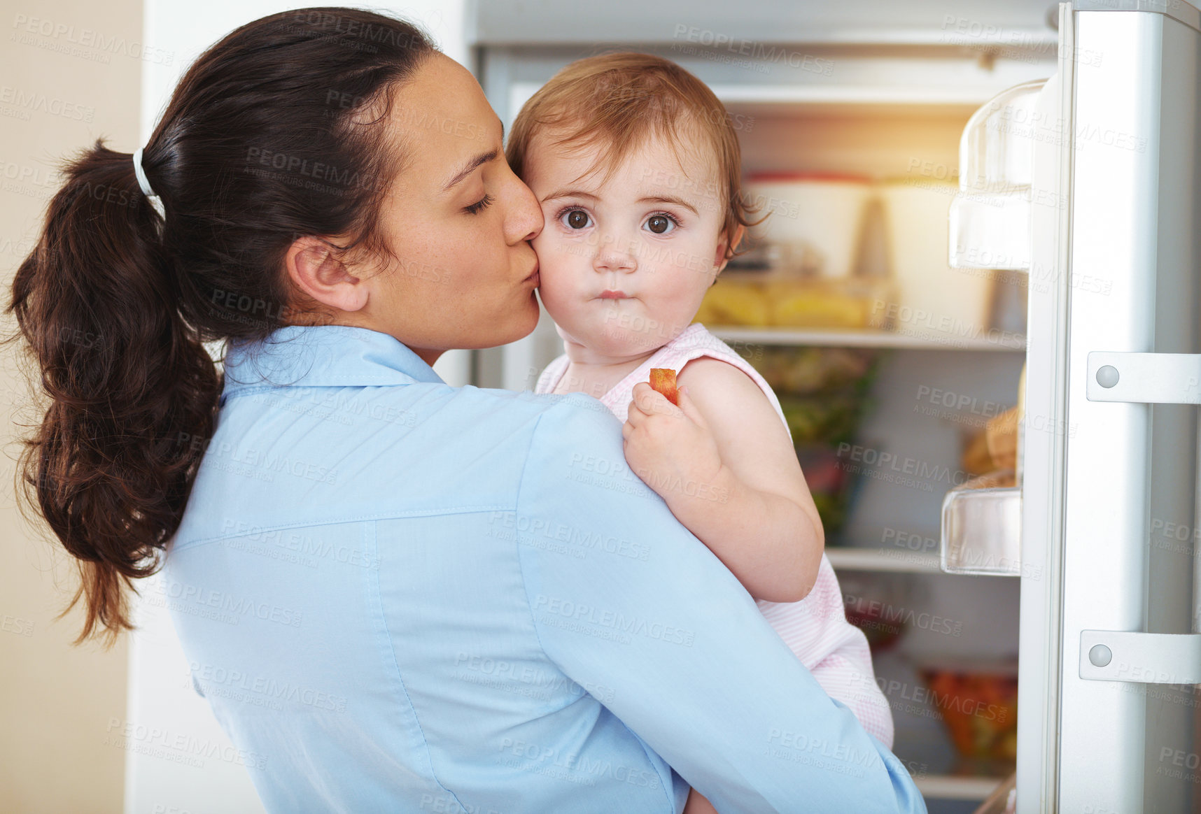 Buy stock photo Happy woman, mother and toddler with kiss in kitchen, fridge and eating of snack for hunger. Kid, little girl and hungry with fresh, organic or fruit for nutrition, vegetarian or healthy diet in home