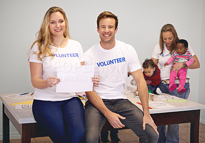 Buy stock photo Shot of volunteers holding up a blank sign while working with little children