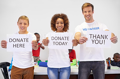 Buy stock photo Portrait of volunteers holding up  signs while working with little children