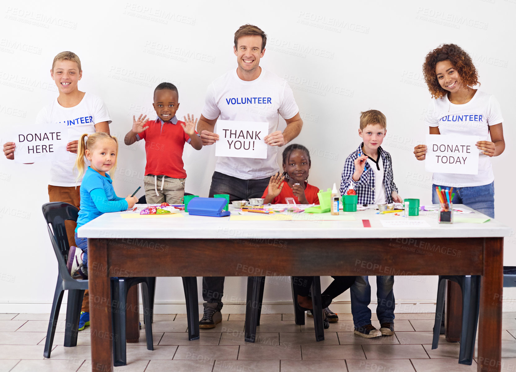 Buy stock photo Portrait of volunteers holding up  signs while working with little children