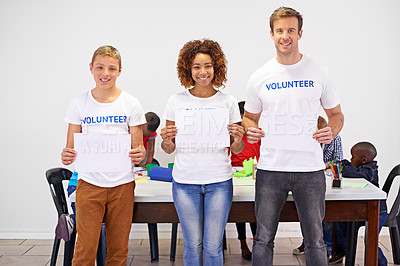 Buy stock photo Portrait of volunteers holding up a blank sign while working with little children
