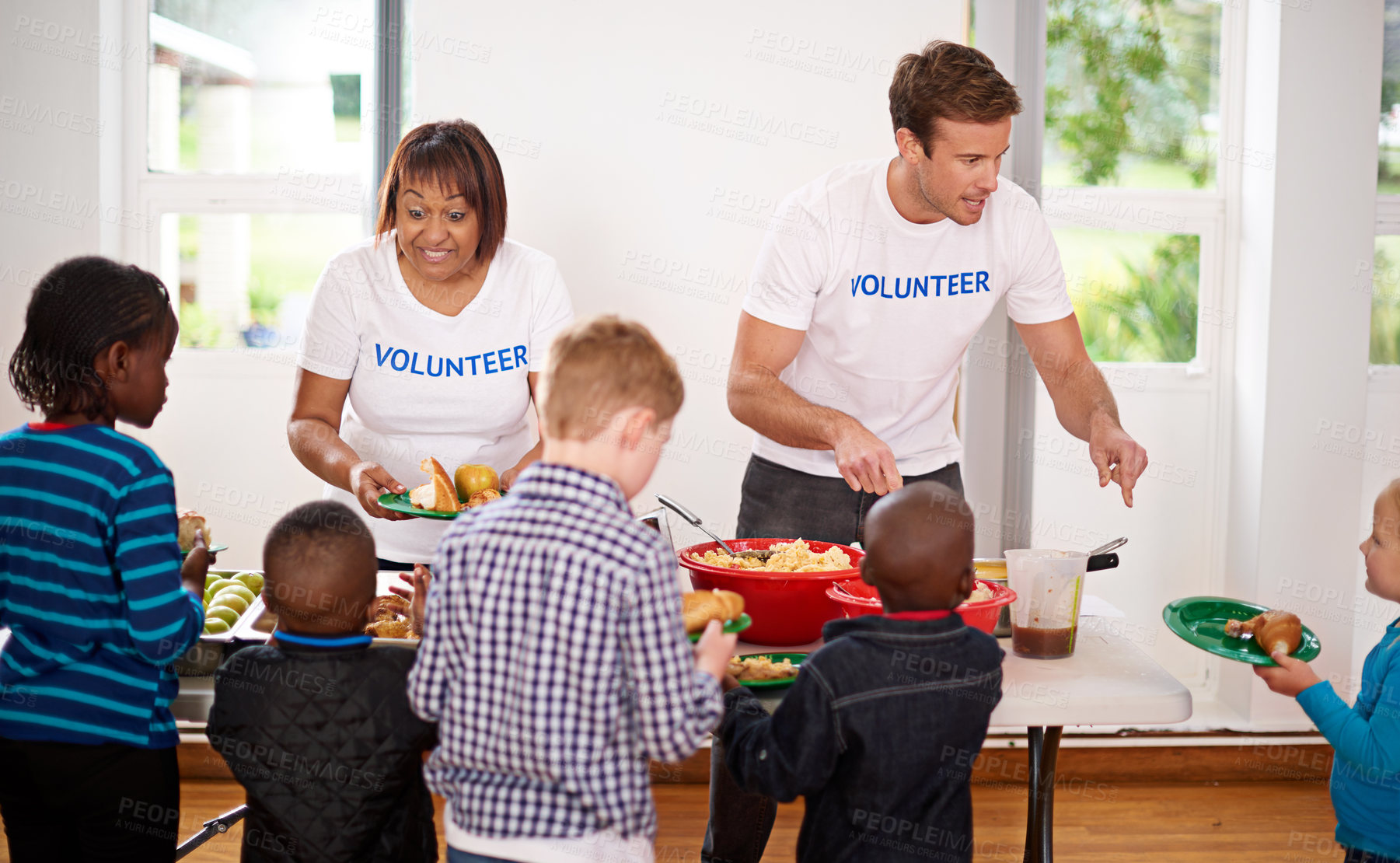 Buy stock photo Shot of volunteers serving food to a group of little children