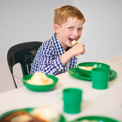 Buy stock photo Portrait of a young boy eating at a volunteer run kitchen