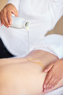 Buy stock photo Shot of a masseuse pouring oil on a woman's back at a spa