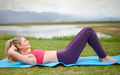 Buy stock photo Shot of a young woman doing sit-ups in the outdoors