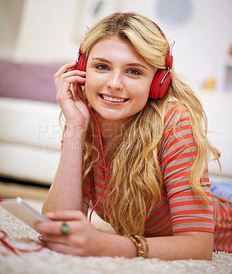 Buy stock photo Cropped portrait of a young woman listening to music on her cellphone at home