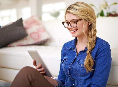 Buy stock photo Cropped shot of a young woman using her tablet at home