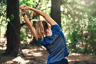 Buy stock photo Shot of a young woman warming up for a trail run