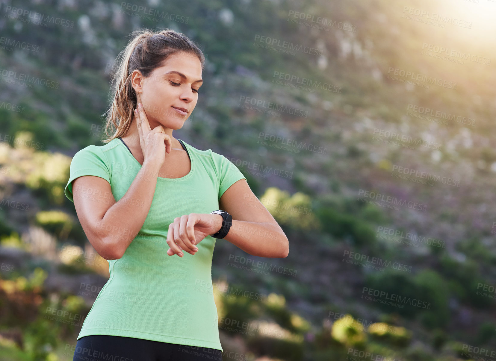 Buy stock photo Shot of a young woman checking her heart rate while exercising outdoors