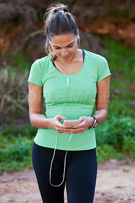 Buy stock photo Woman, fitness and phone for listening to music, exercise and workout outdoor in forest or park with health tracker. Person or runner typing, search or scroll on mobile app for audio and training